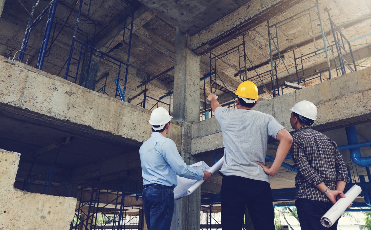 Tre personer taler på byggeplads