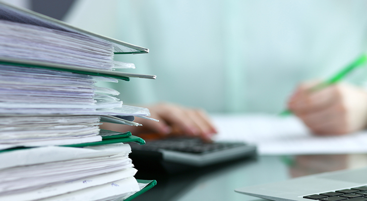 Person sidder med lommeregner og mapper