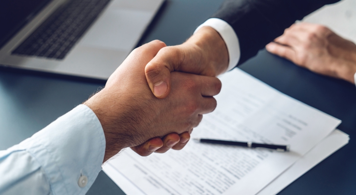 Håndtryk på aftale med kontrakt liggende under