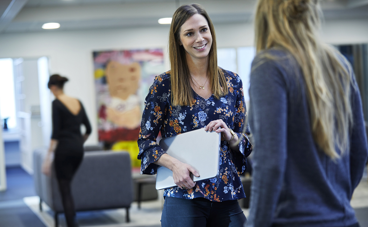 Mette Myrup med bærbar computer under armen snakker med kvinde