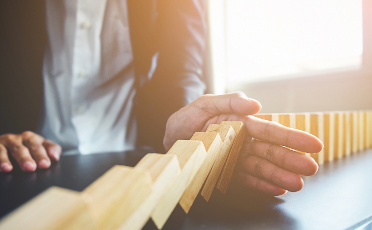 Person holder hånden for væltende dominoklodser 