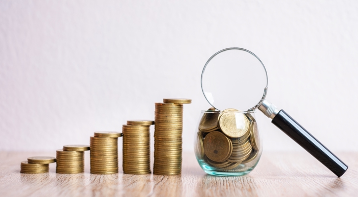 Fem stakke af mønter og et glas med mønter og en loop ovenpå